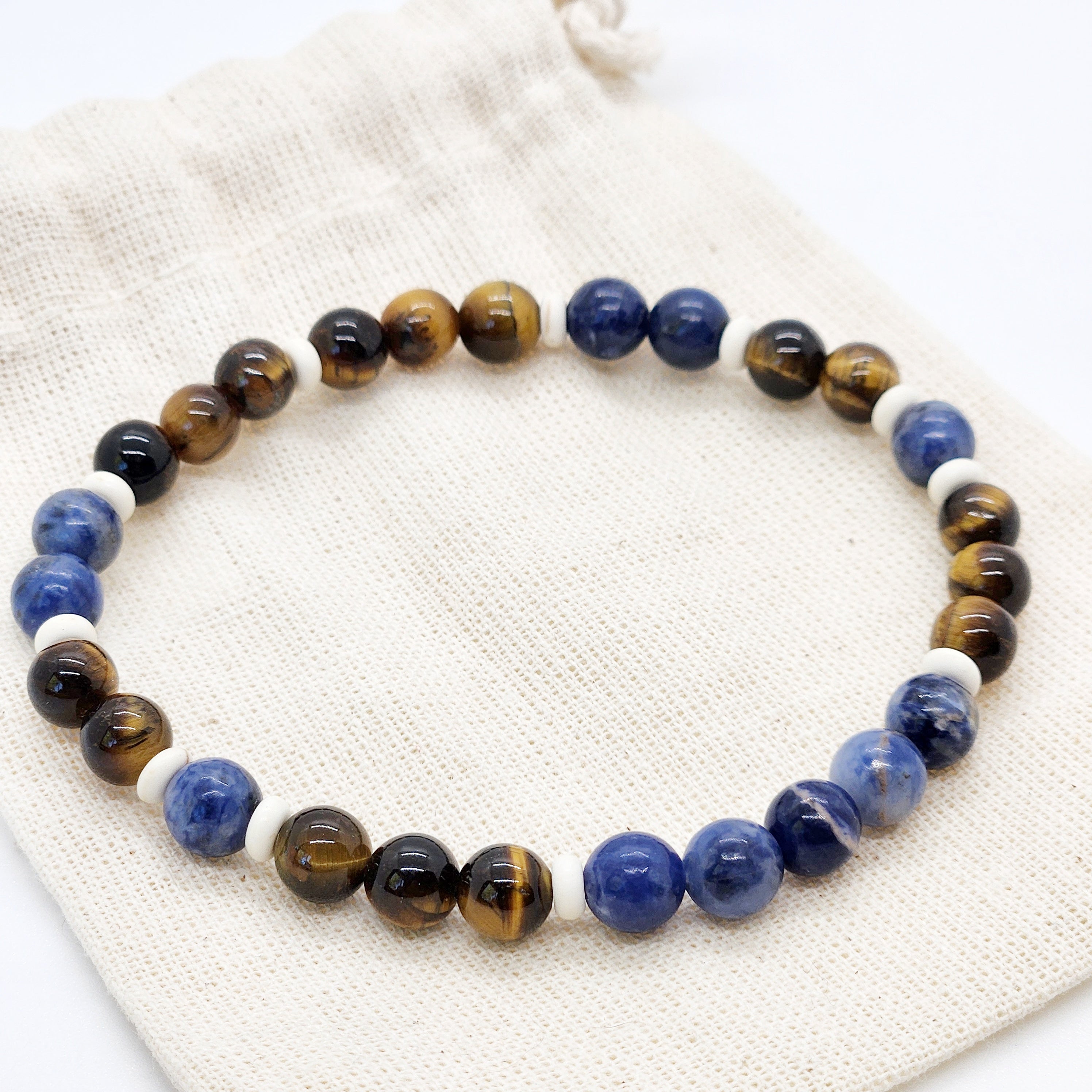 Beaded bracelet with blue, brown, and white beads on a textured fabric background