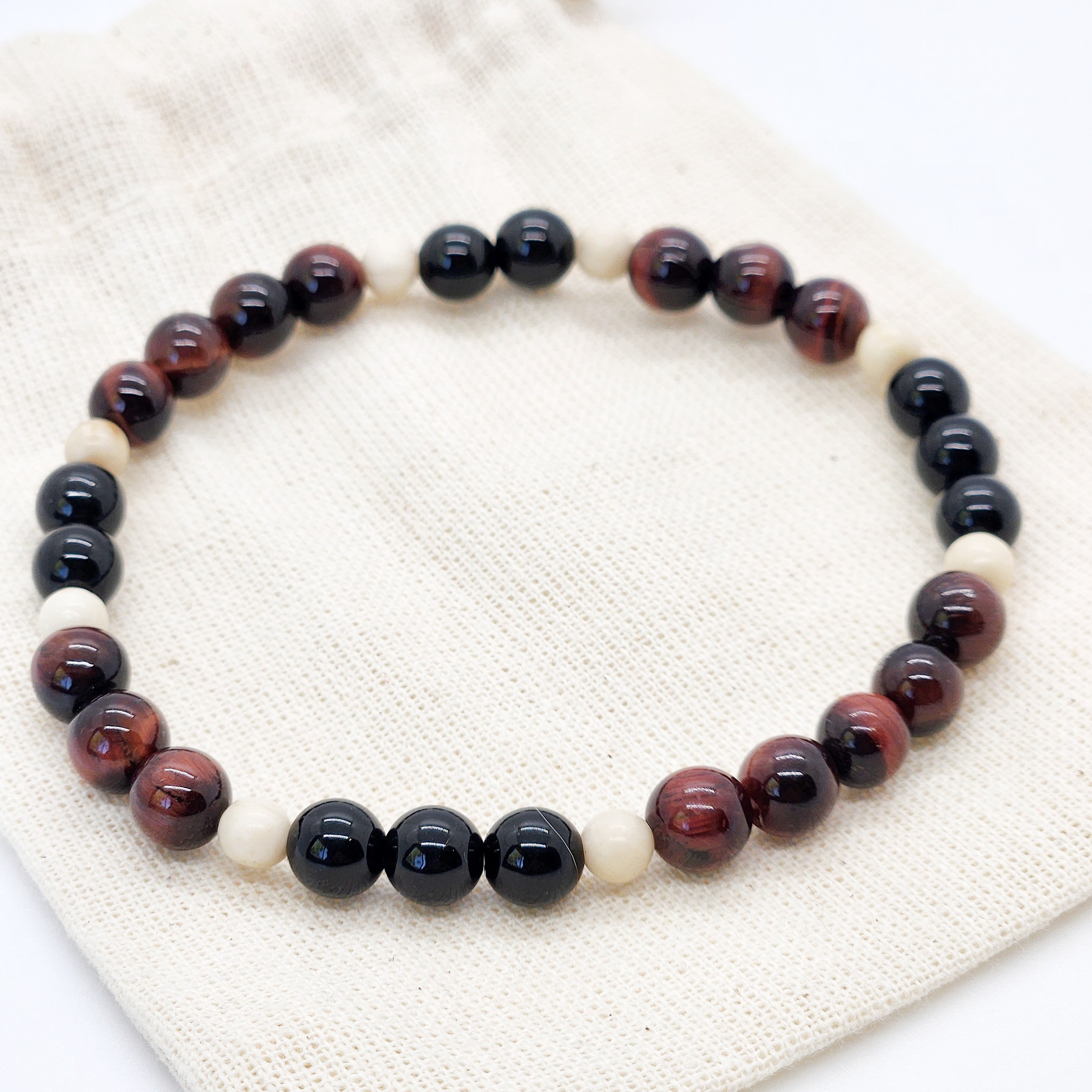 Beaded bracelet with black, brown, and white beads on a textured fabric background