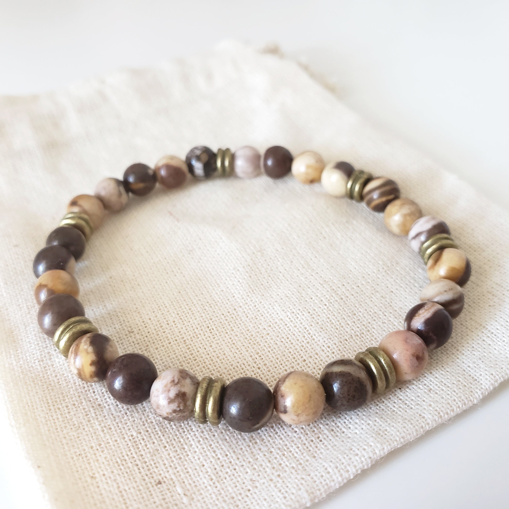 Beaded bracelet with brown, beige, and bronze beads on a white fabric background