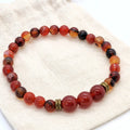Beaded bracelet with red, orange, and black beads on a textured fabric background