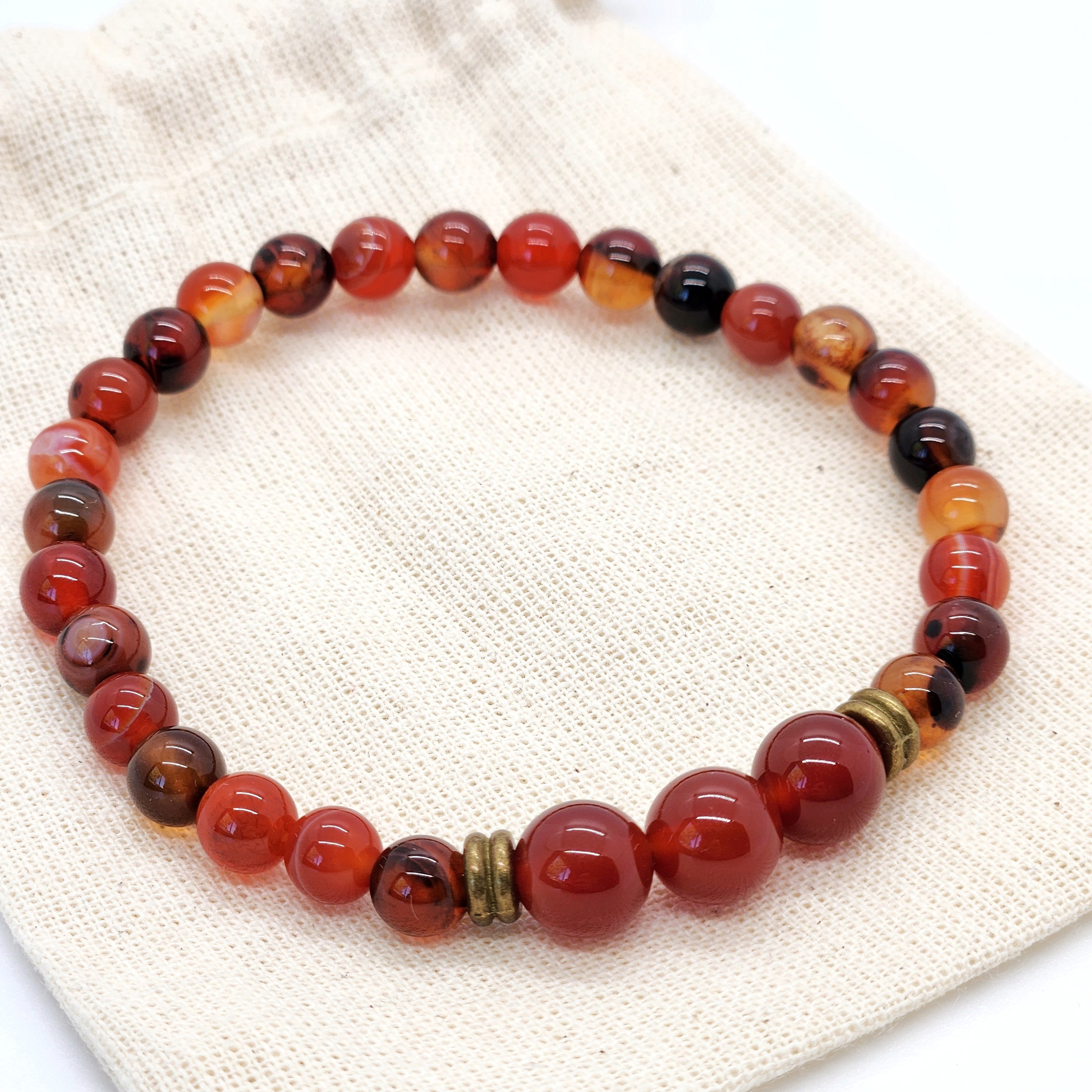 Beaded bracelet with red, orange, and black beads on a textured fabric background