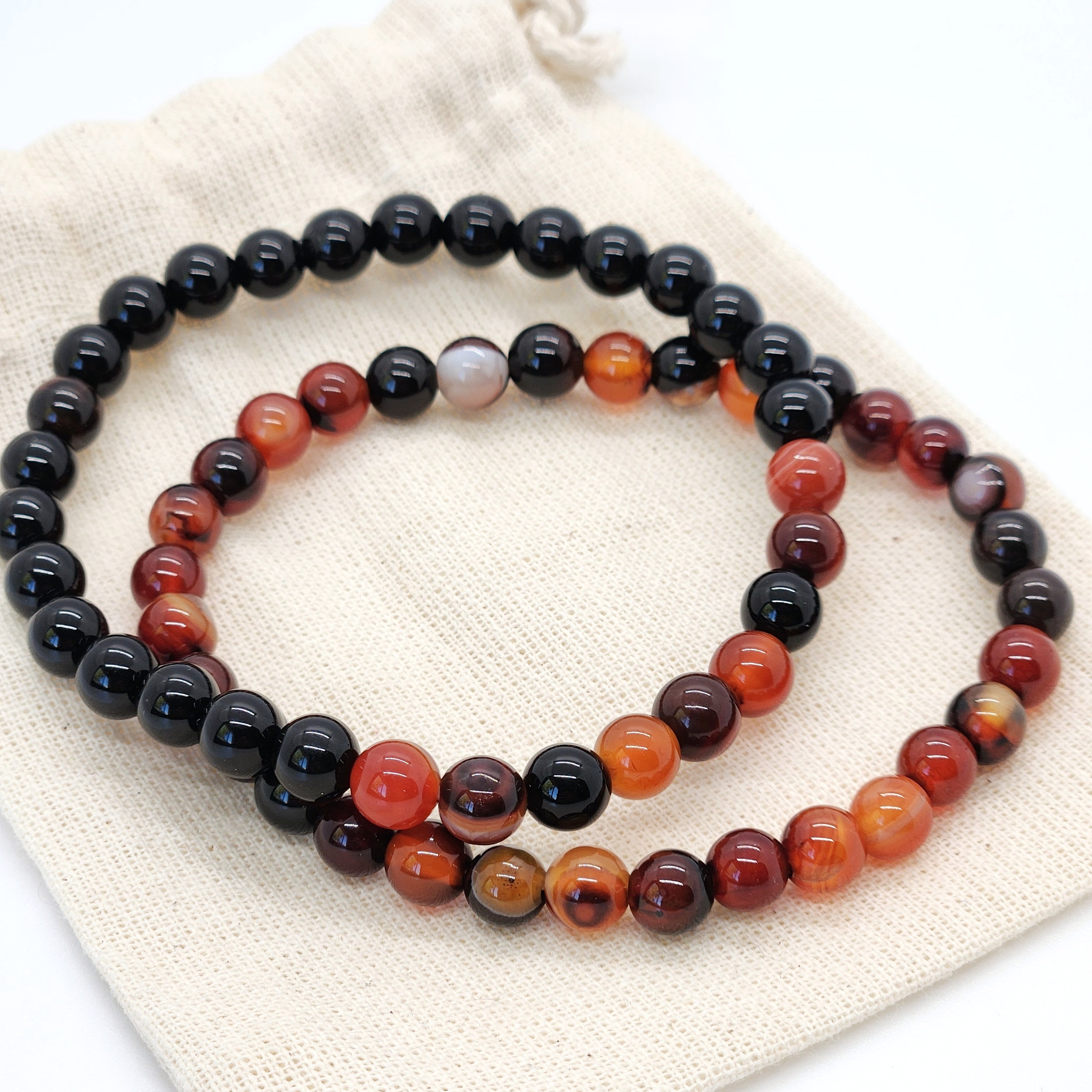 Two beaded bracelets on a white fabric background