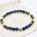 Beaded bracelet with blue, green, and white beads on a textured surface