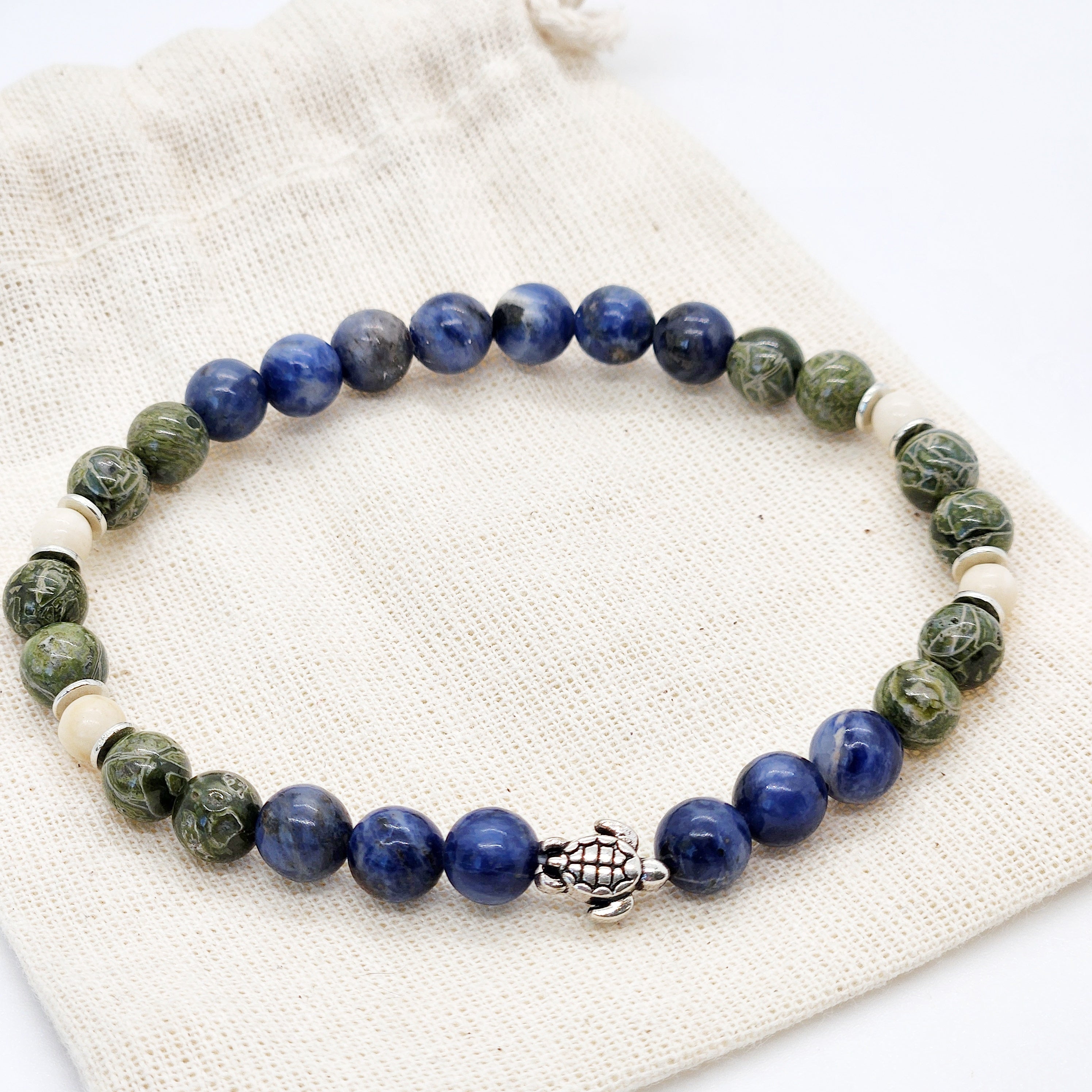 Beaded bracelet with blue, green, and white beads on a textured surface